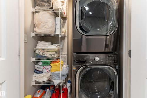 Integrated laundry area featuring a stacked washer and dryer unit, white wire shelving, and a clean, light-toned wall finish - 2520 152 Avenue, Edmonton, AB 