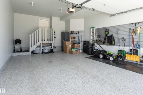 Spacious garage featuring a durable epoxy-coated floor, slat wall organization system, and interior access staircase - 2520 152 Avenue, Edmonton, AB 