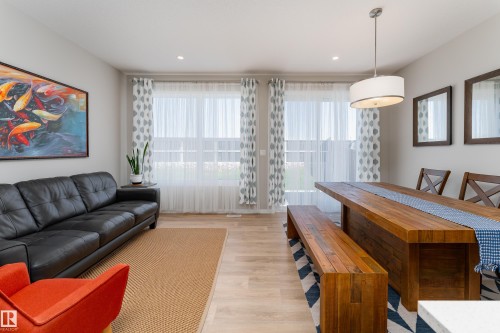 Open-concept living and dining area featuring light-toned wood-finish laminate flooring, recessed lighting, and a modern drum pendant light - 2520 152 Avenue, Edmonton, AB 
