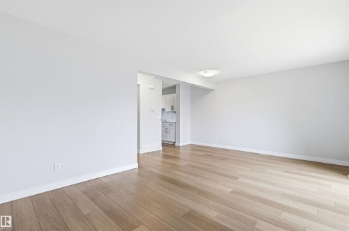 Spacious interior featuring wide plank wood-finish flooring, white baseboards, and neutral wall paint - 18353 66 Avenue, Edmonton, AB 