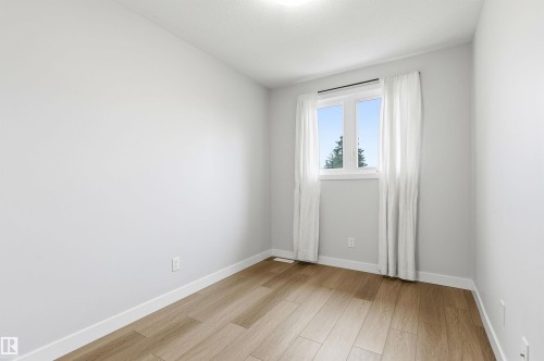 Bright room featuring a window with white trim, wood-finish flooring, and light-colored walls - 18353 66 Avenue, Edmonton, AB 