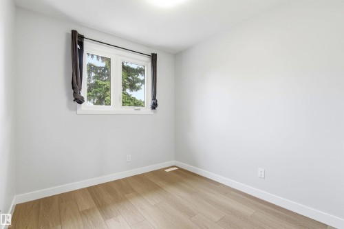 Light-filled room featuring wood-finish flooring, white baseboards, and a white-framed window - 18353 66 Avenue, Edmonton, AB 