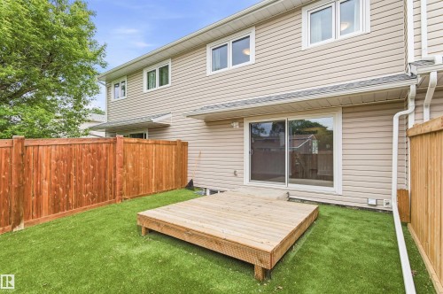 Rear exterior featuring a wooden deck, artificial turf, and a sliding glass door - 18353 66 Avenue, Edmonton, AB 