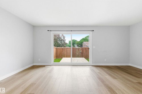 Spacious interior room with light wood-finish flooring, white baseboards, and light gray painted walls - 18353 66 Avenue, Edmonton, AB 