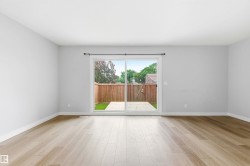 Spacious interior room with light wood-finish flooring, white baseboards, and light gray painted walls - 