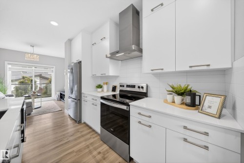 Modern kitchen featuring white cabinetry, stainless steel appliances, white subway tile backsplash, and light wood-finish flooring - 52 1729 Keene Crescent, Edmonton, AB 