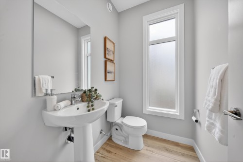 White pedestal sink with a chrome faucet, full-height wall mirror, and plank-style flooring - 52 1729 Keene Crescent, Edmonton, AB 
