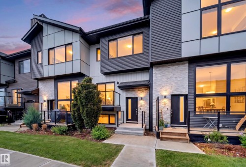 Modern townhome exterior with mixed material facade, featuring wide windows, a private ground-level patio, and contemporary front entry doors - 52 1729 Keene Crescent, Edmonton, AB 