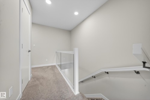 Upper hallway featuring a contemporary glass panel railing system, white trim, recessed lighting, and neutral carpet flooring - 52 1729 Keene Crescent, Edmonton, AB 