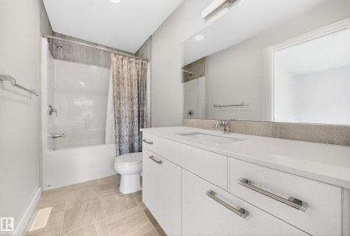 Contemporary bathroom featuring a white vanity with integrated sink, a large mirror, and a tub-shower combination with tiled surround - 52 1729 Keene Crescent, Edmonton, AB 