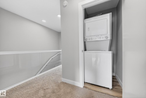 Dedicated laundry closet featuring a white stacked washer and dryer unit - 52 1729 Keene Crescent, Edmonton, AB 
