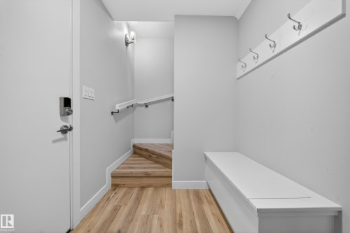 Entryway featuring wood-finish flooring, a built-in storage bench, and a wall-mounted coat rack - 52 1729 Keene Crescent, Edmonton, AB 