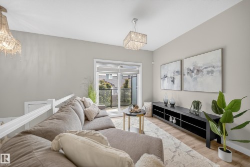 Open-concept living space featuring wood-finish flooring, a sliding glass door leading to a balcony, and contemporary lighting fixtures - 52 1729 Keene Crescent, Edmonton, AB 