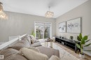 Open-concept living space featuring wood-finish flooring, a sliding glass door leading to a balcony, and contemporary lighting fixtures - 52 1729 Keene Crescent, Edmonton, AB 