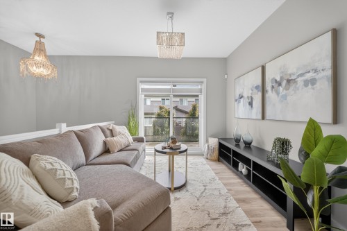 Living area featuring light wood-finish flooring, light grey wall paint, and a sliding glass door leading to a balcony - 52 1729 Keene Crescent, Edmonton, AB 