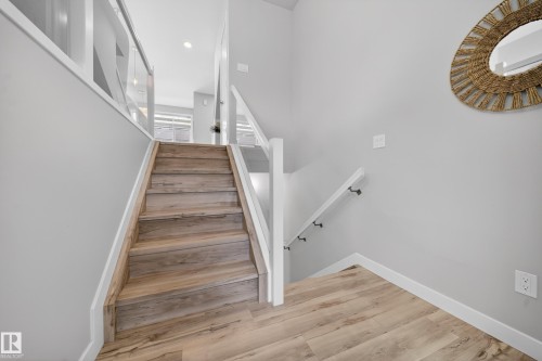 Staircase featuring wood-finish treads and risers, white trim, and a glass-paneled railing - 52 1729 Keene Crescent, Edmonton, AB 