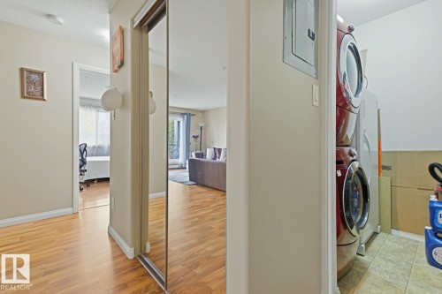 Entryway featuring wood-finish flooring, a full-length mirrored closet door, and neutral-toned walls - 211 1204 156 Street Nw, Edmonton, AB 
