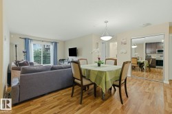 Open-concept living area with wood-finish flooring, a contemporary dining light fixture, and a window with a balcony - 