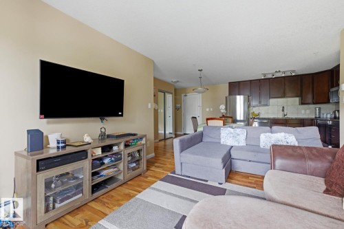 Open-concept living space featuring wood-finish flooring, a neutral wall color, and recessed lighting - 211 1204 156 Street Nw, Edmonton, AB 