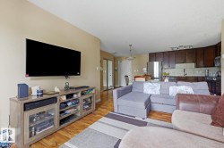 Open-concept living space featuring wood-finish flooring, a neutral wall color, and recessed lighting - 