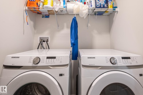 Dedicated laundry area featuring a front-loading washer and dryer set, overhead wire shelving, and neutral wall finishes - 17562 63A Street, Edmonton, AB 