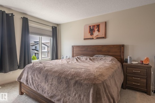 Bedroom featuring light-toned walls, textured ceiling, a window with horizontal blinds, and carpeted flooring - 17562 63A Street, Edmonton, AB 