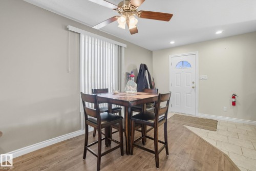 Entry area featuring a white panel door with an arched window, wood-finish flooring, and a ceiling fan with light fixture - 14239 53 Street, Edmonton, AB 