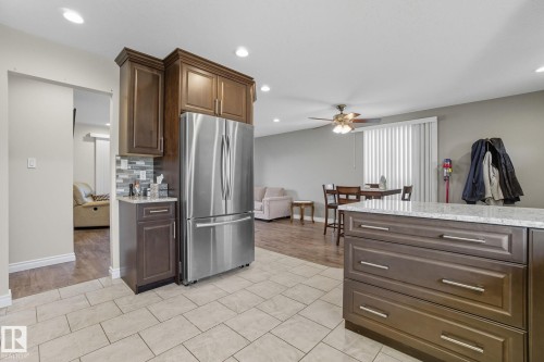Kitchen featuring contemporary light-toned tile flooring, dark wood-finish cabinetry, a stainless steel French door refrigerator, and a mosaic tile backsplash - 14239 53 Street, Edmonton, AB 