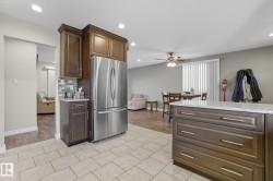 Kitchen featuring contemporary light-toned tile flooring, dark wood-finish cabinetry, a stainless steel French door refrigerator, and a mosaic tile backsplash - 