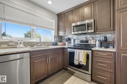 Kitchen featuring brown cabinetry, stainless steel appliances, speckled countertops, and a tiled backsplash - 