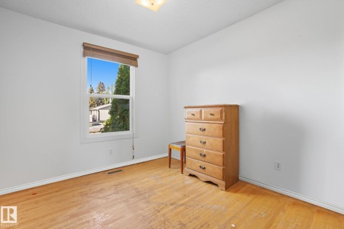 Light-filled room featuring a large window with wooden blinds, white painted walls, and wood-finish flooring - 14239 53 Street, Edmonton, AB 