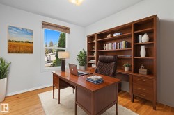 Dedicated space featuring extensive built-in wood shelving and storage, wood-finish flooring, a double-pane window with wood blinds, and crisp white baseboards - 