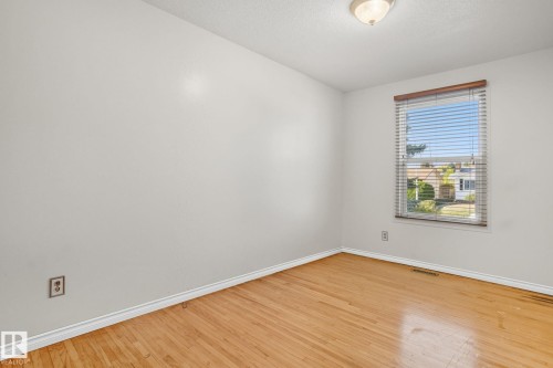 Room featuring wood-finish flooring, a window with blinds, and a ceiling-mounted light fixture - 14239 53 Street, Edmonton, AB 