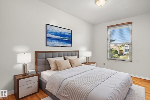 Bright bedroom featuring a single window with blinds, wood-finish flooring, and a ceiling-mounted light fixture - 14239 53 Street, Edmonton, AB 