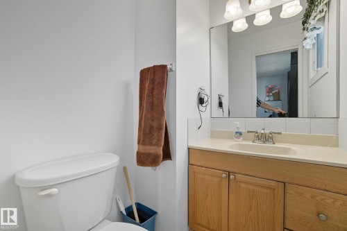 Bathroom vanity with wood-finish cabinetry, a built-in sink, and a light-toned countertop - 14239 53 Street, Edmonton, AB 
