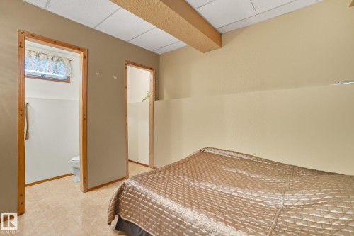 Room featuring a drop ceiling with a visible beam, two doorways with wood trim, and a window with a valance - 14239 53 Street, Edmonton, AB 