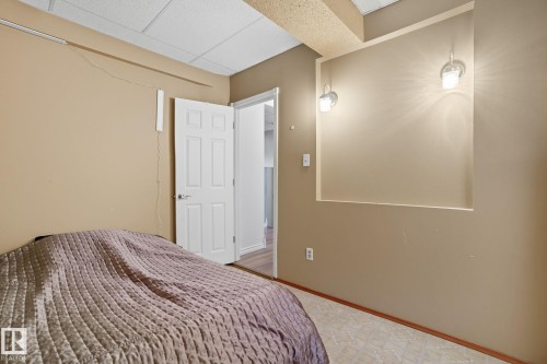 Recessed wall niche with two wall-mounted sconces, neutral wall finishes, white paneled door, and patterned tile flooring - 14239 53 Street, Edmonton, AB 