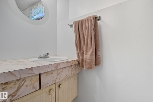 Vanity featuring a drop-in sink, chrome faucet, and a patterned countertop - 14239 53 Street, Edmonton, AB 