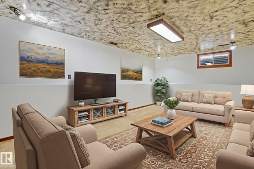 Spacious lower-level room featuring a decorative ceiling, recessed lighting, and a functional window with wood trim - 14239 53 Street, Edmonton, AB 
