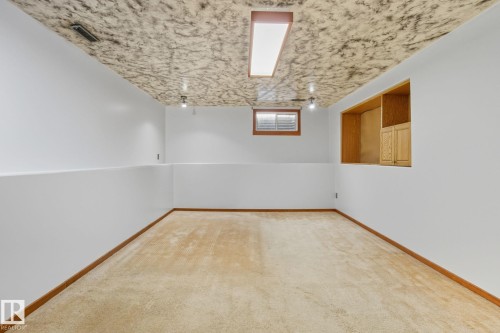 Spacious room featuring light-colored carpeting, white baseboards, and a drop ceiling with recessed lighting - 14239 53 Street, Edmonton, AB 