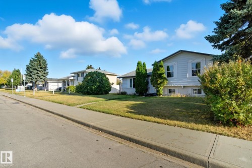 Split-level residence featuring light-colored siding, a dark roofline, and multiple windows - 14239 53 Street, Edmonton, AB 