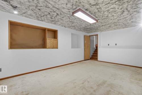 Spacious room featuring light-toned carpeting, white walls, and a textured ceiling - 14239 53 Street, Edmonton, AB 