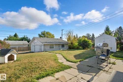 Expansive backyard featuring a concrete patio, stepping stone pathway, and a detached storage shed - 14239 53 Street, Edmonton, AB 