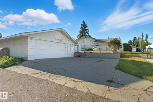 Detached garage with horizontal siding, a double garage door, and an exterior side door - 14239 53 Street, Edmonton, AB 