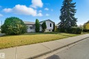 White split-level residence featuring a gray shingle roof and a concrete sidewalk - 14239 53 Street, Edmonton, AB 