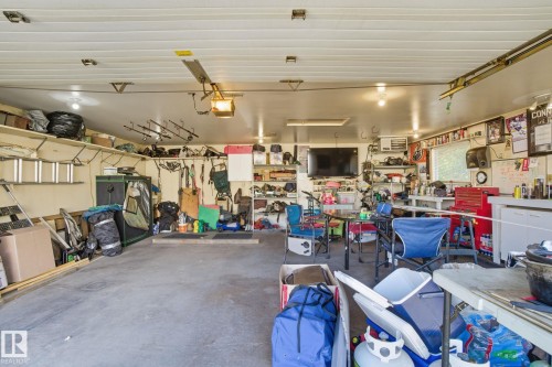 Two-car garage featuring a concrete floor, built-in shelving, mounted lighting, and a utility window - 14239 53 Street, Edmonton, AB 