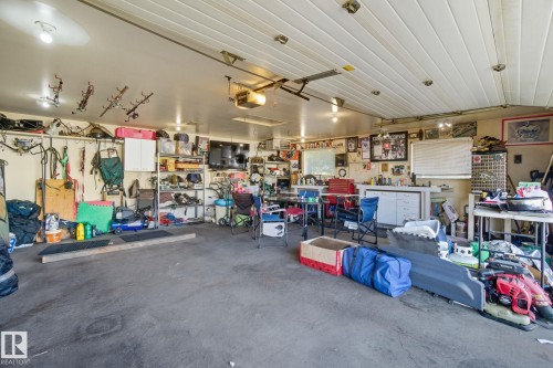 Spacious garage featuring a concrete floor, slatted ceiling, and ample overhead lighting - 14239 53 Street, Edmonton, AB 