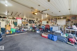 Spacious garage featuring a concrete floor, slatted ceiling, and ample overhead lighting - 