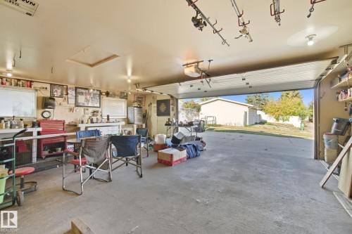 Spacious garage featuring concrete flooring, built-in shelving, and a large overhead door - 14239 53 Street, Edmonton, AB 
