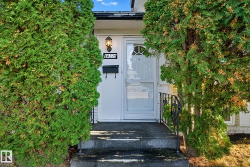 White front door with an arched transom window and a black storm door - 14239 53 Street, Edmonton, AB 